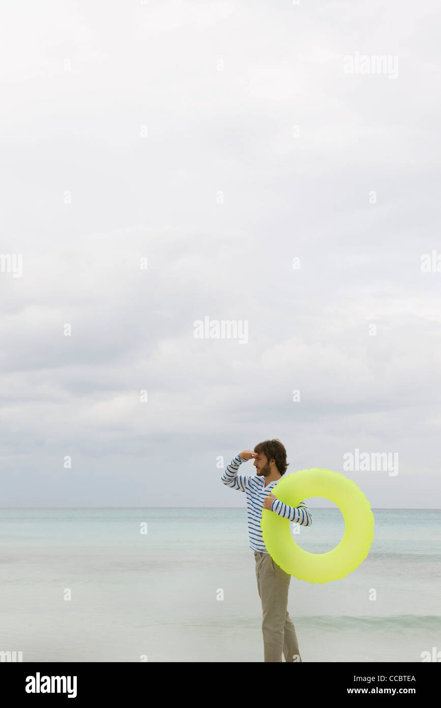 Junger Mann mit aufblasbaren schwimmen Ring Blick in Ferne Stockfoto