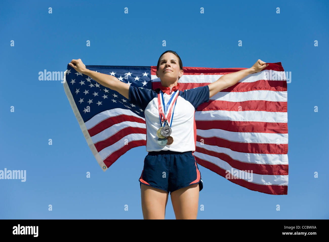 Weiblichen Athleten geehrt auf Podest, amerikanische Fahne hochhalten Stockfoto