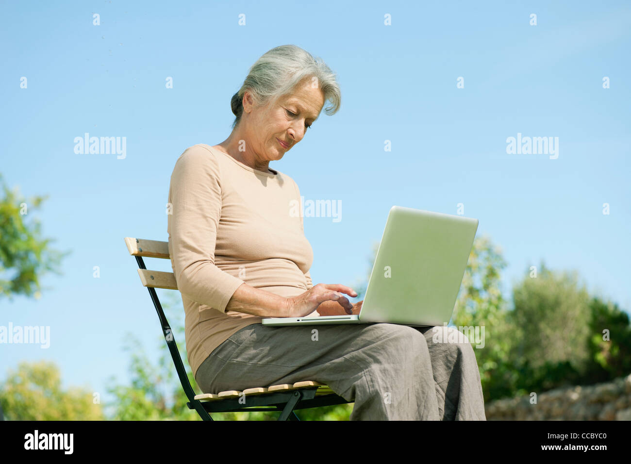 Ältere Frau mit Laptop im freien Stockfoto