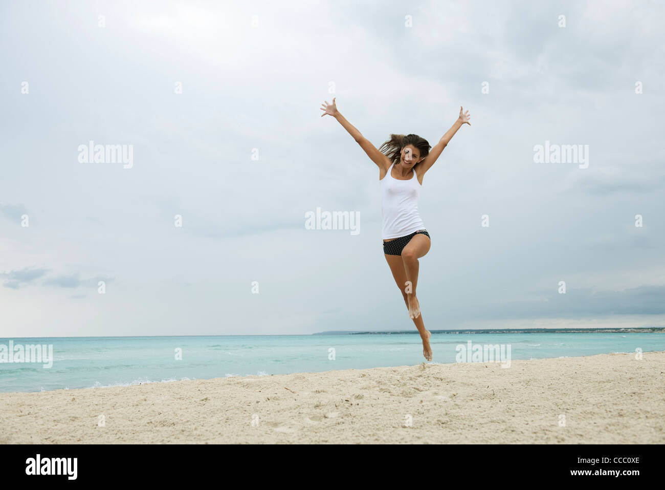 Junge Frau am Strand in die Luft springen Stockfoto
