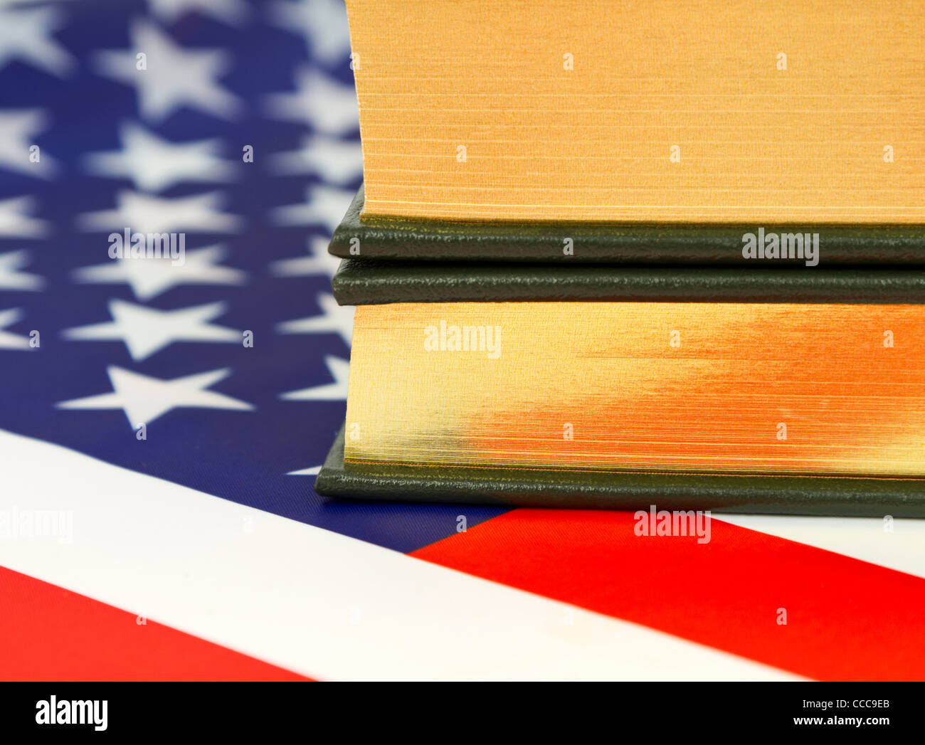Nahaufnahme von Büchern mit Goldrand-Seiten auf eine amerikanische Flagge gesetzt. Stockfoto