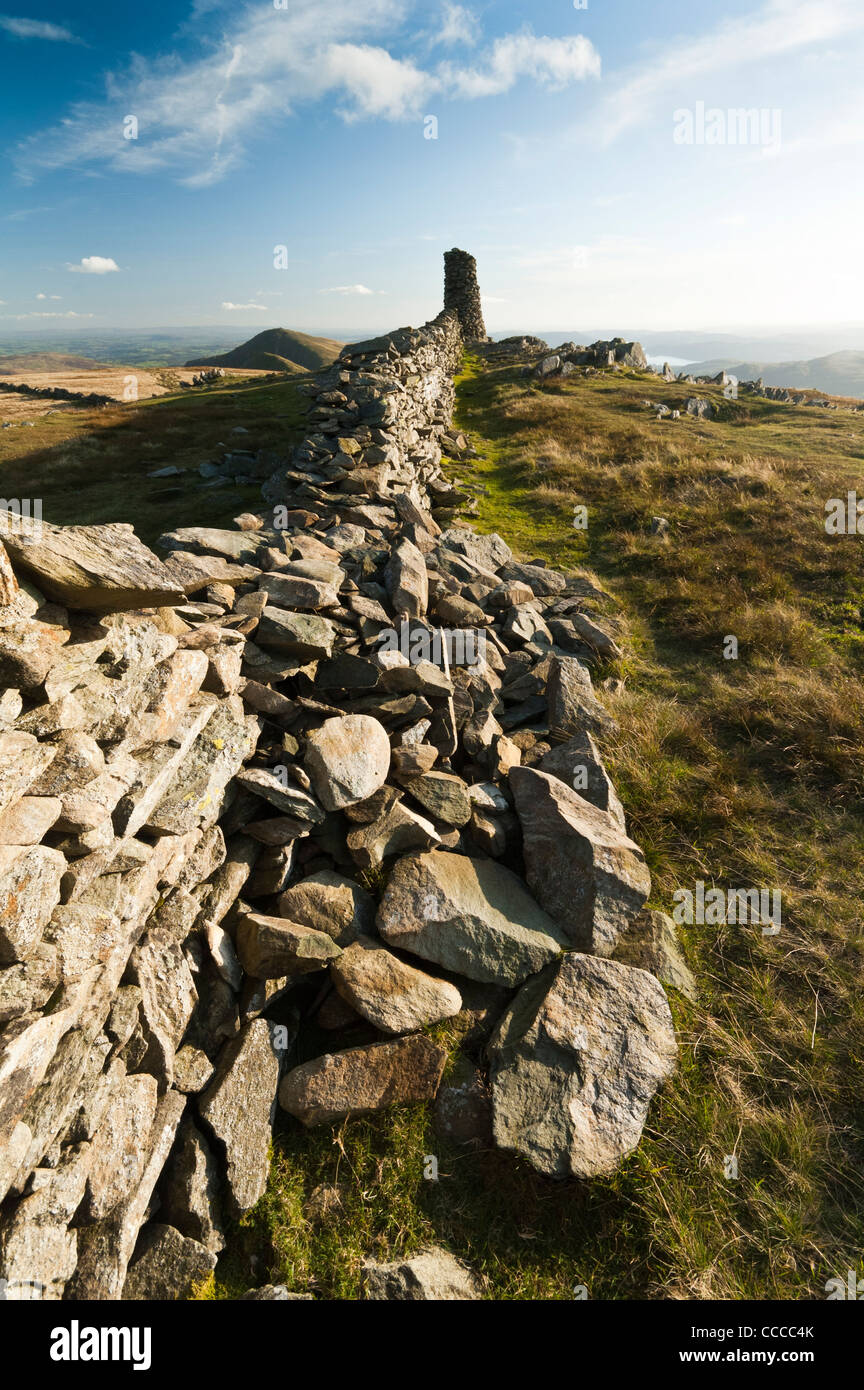 Gipfel des "High Street" in den Cumbrian Hügeln mit Blick auf einen sehr großen Cairn am Ende eine beschädigte Trockenmauer. Stockfoto