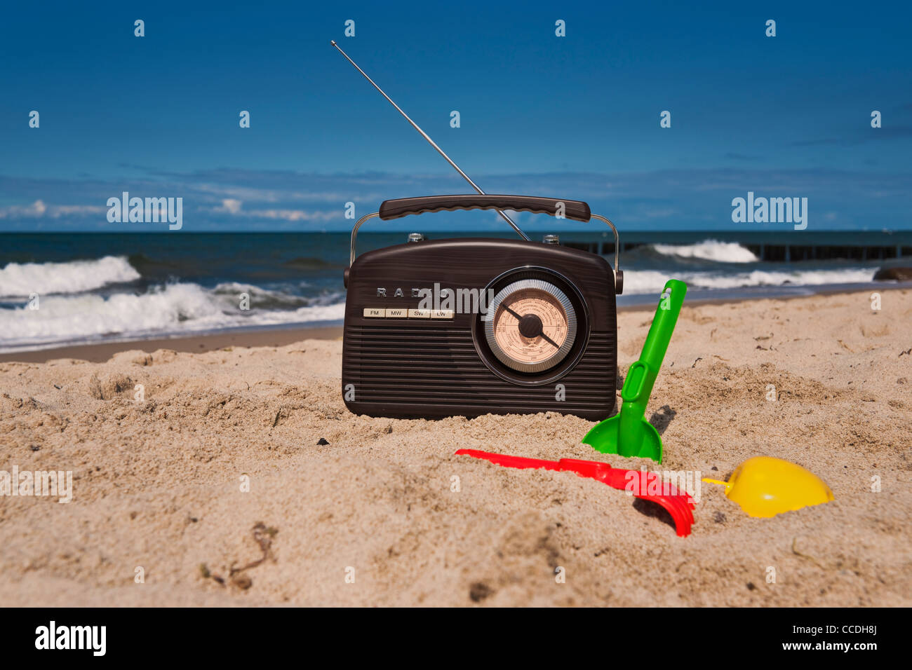 Ein Radio Steht bin Sandstrand, Strandspielzeug so Lebenswege | ein Radio ist am Sandstrand, Spielzeug für den Strand entlang Stockfoto