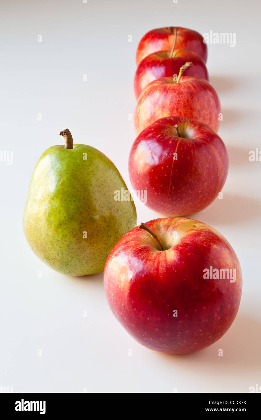Grüne Birne stehend aus einer Reihe von roten Äpfeln. Stockfoto
