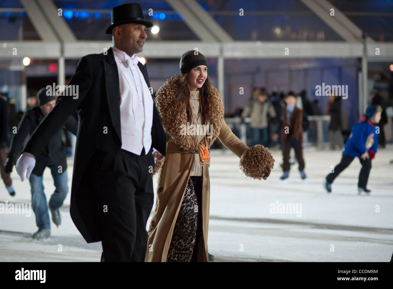 Skater in formelle Kleidung gekleidet manövrieren die gepackten Teich am Eislaufplatz der Bryant Park in New York Stockfoto