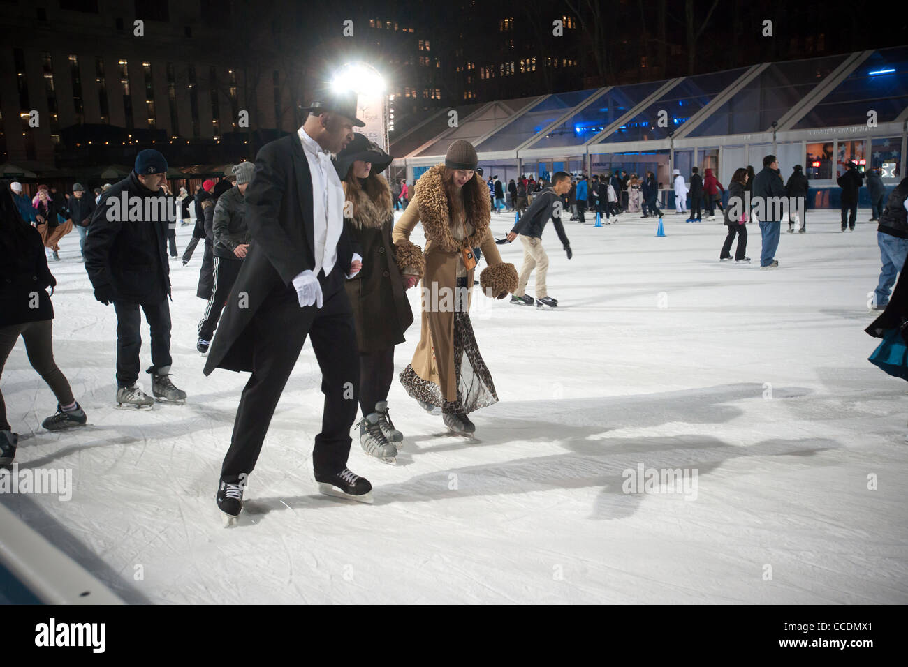 Skater in formelle Kleidung gekleidet manövrieren die gepackten Teich am Eislaufplatz der Bryant Park in New York Stockfoto