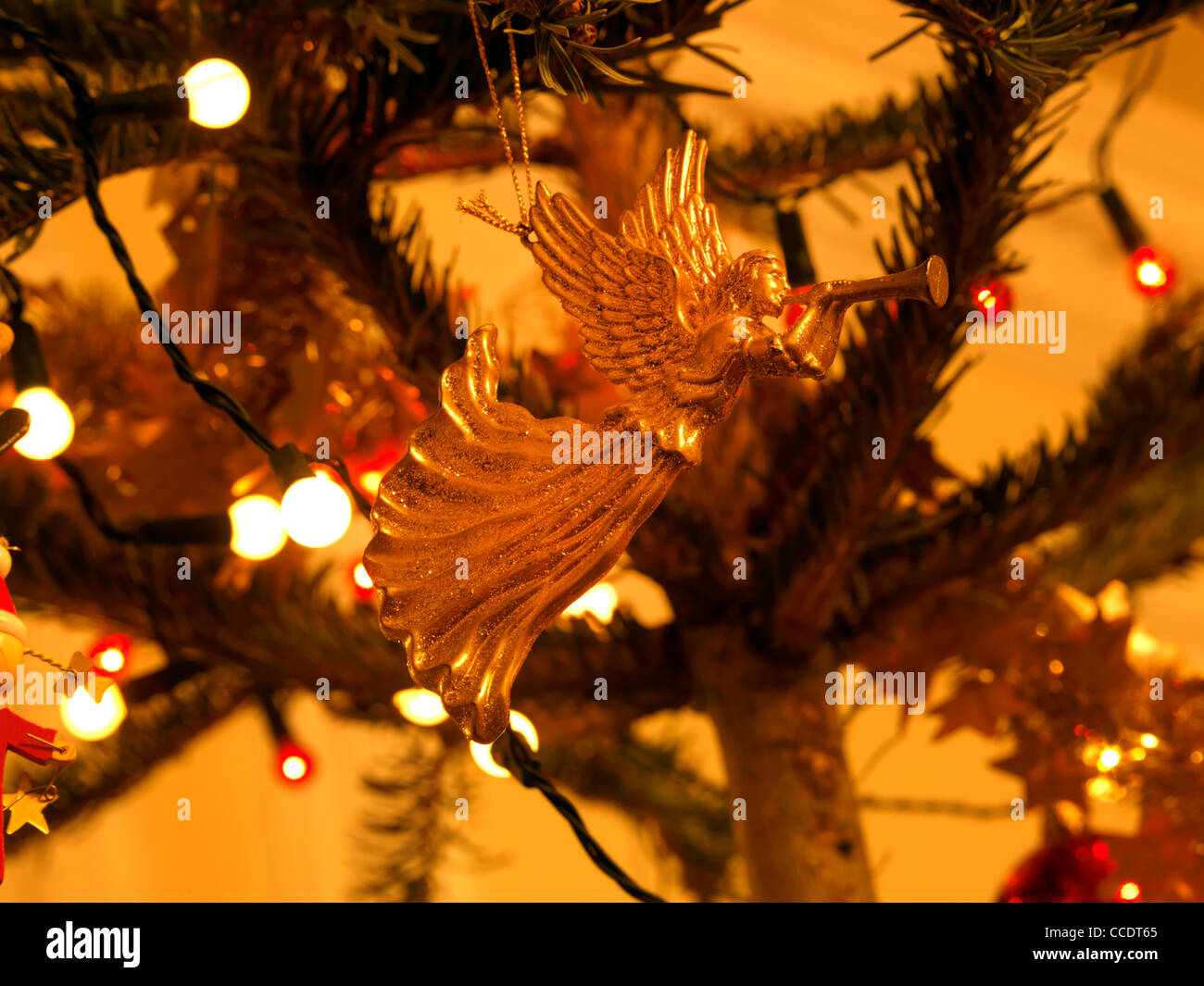 Gold Engel-Weihnachtsschmuck hängt an einem Baum und Weihnachten leuchtet Stockfoto