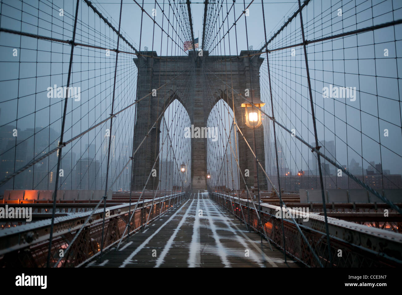 Die Brooklyn Bridge mit Schnee in der Morgendämmerung mit Manhattan im Hintergrund. Stockfoto