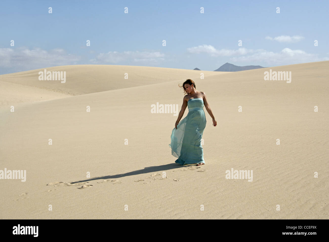 Indonesische Mädchen in einem türkisfarbenen Kleid zu Fuß auf Sanddünen, Fuerteventura, Kanarische Inseln, Spanien. Stockfoto
