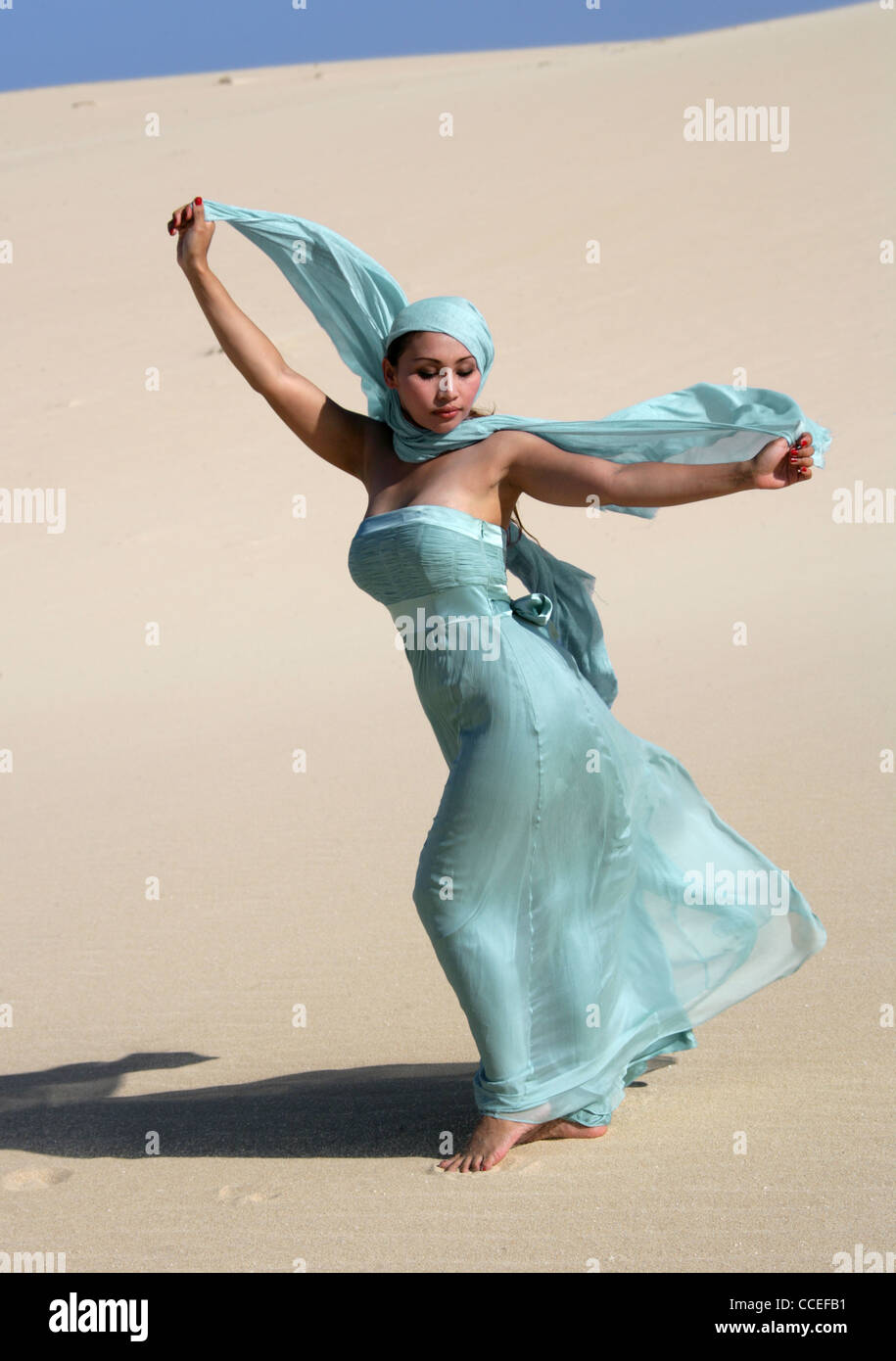 Indonesierin in einem türkisfarbenen Kleid posiert auf Sanddünen, Fuerteventura, Kanarische Inseln, Spanien. Stockfoto