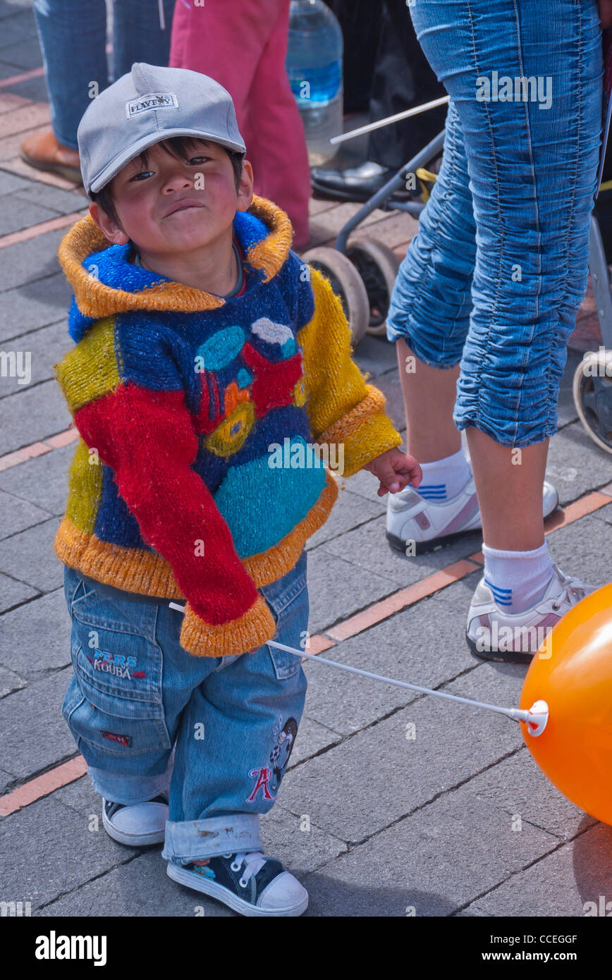 Eine niedliche 3-4 jährige macht ecuadorianischen junge in eine sehr bunte handgemachte Pullover ein lustiges Gesicht mit gedrückter seinen Ballon, Quito. Stockfoto
