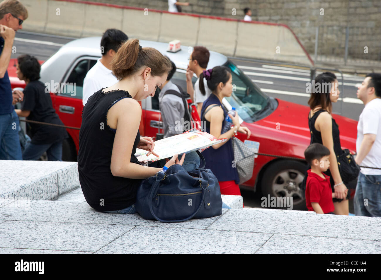 junge weibliche Touristen sitzen Lesung Karte von Hong Kong in der Nähe