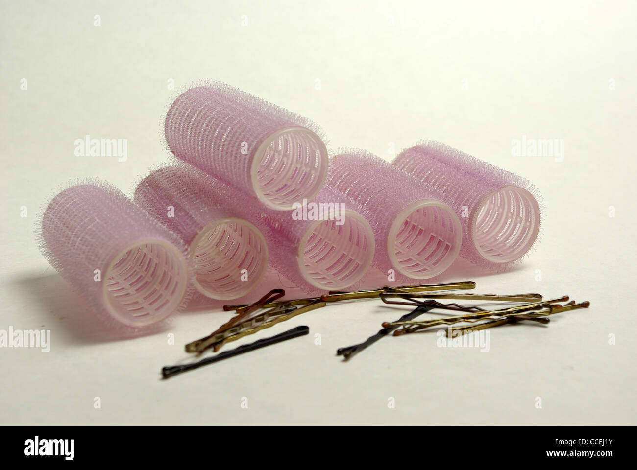 Ein Haufen Lockenwickler und Bobby pins auf einem einfarbigen Hintergrund. Stockfoto
