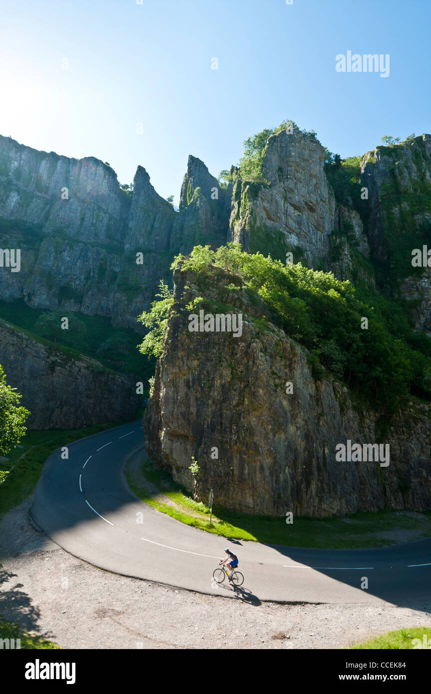 Ein einsamer Radfahrer klettert an einem sonnigen Sommermorgen eine verkehrsfreie Straße durch die dramatische Cheddar-Schlucht. Stockfoto