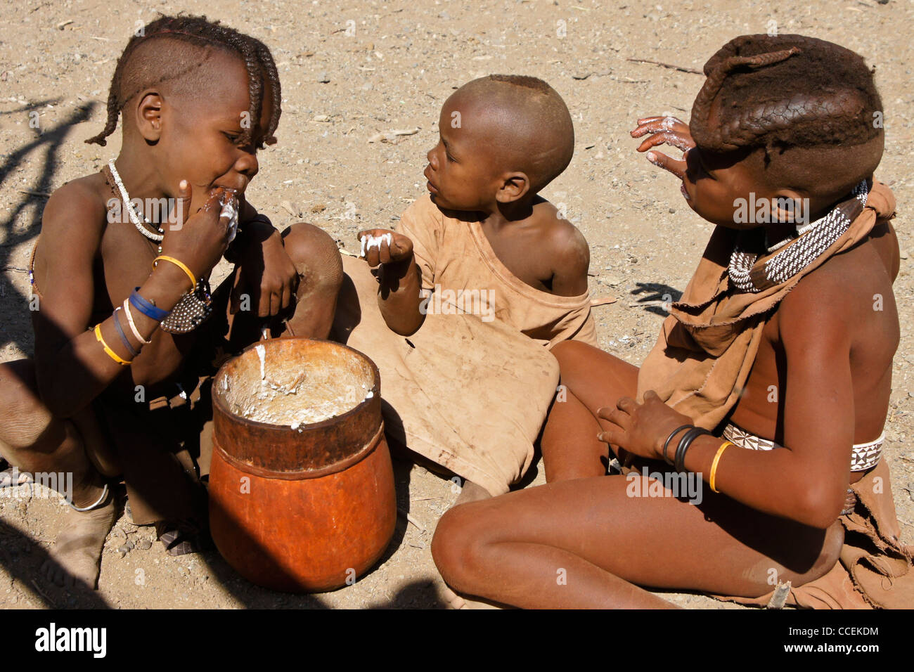 Himba-Kinder essen Maisbrei im Dorf in der Nähe von Opuwo, Namibia Stockfoto