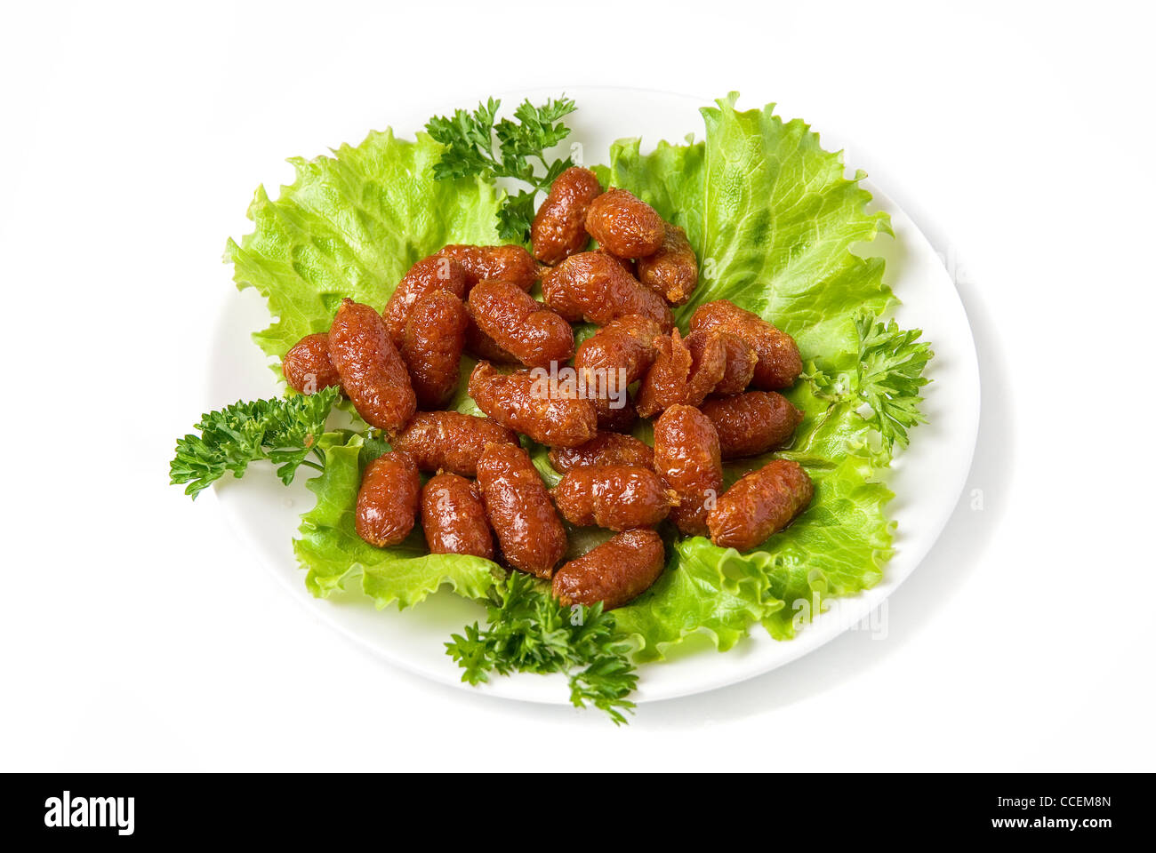 gegrillte Würstchen auf grünem Salat mit isoliert auf weiss Stockfoto
