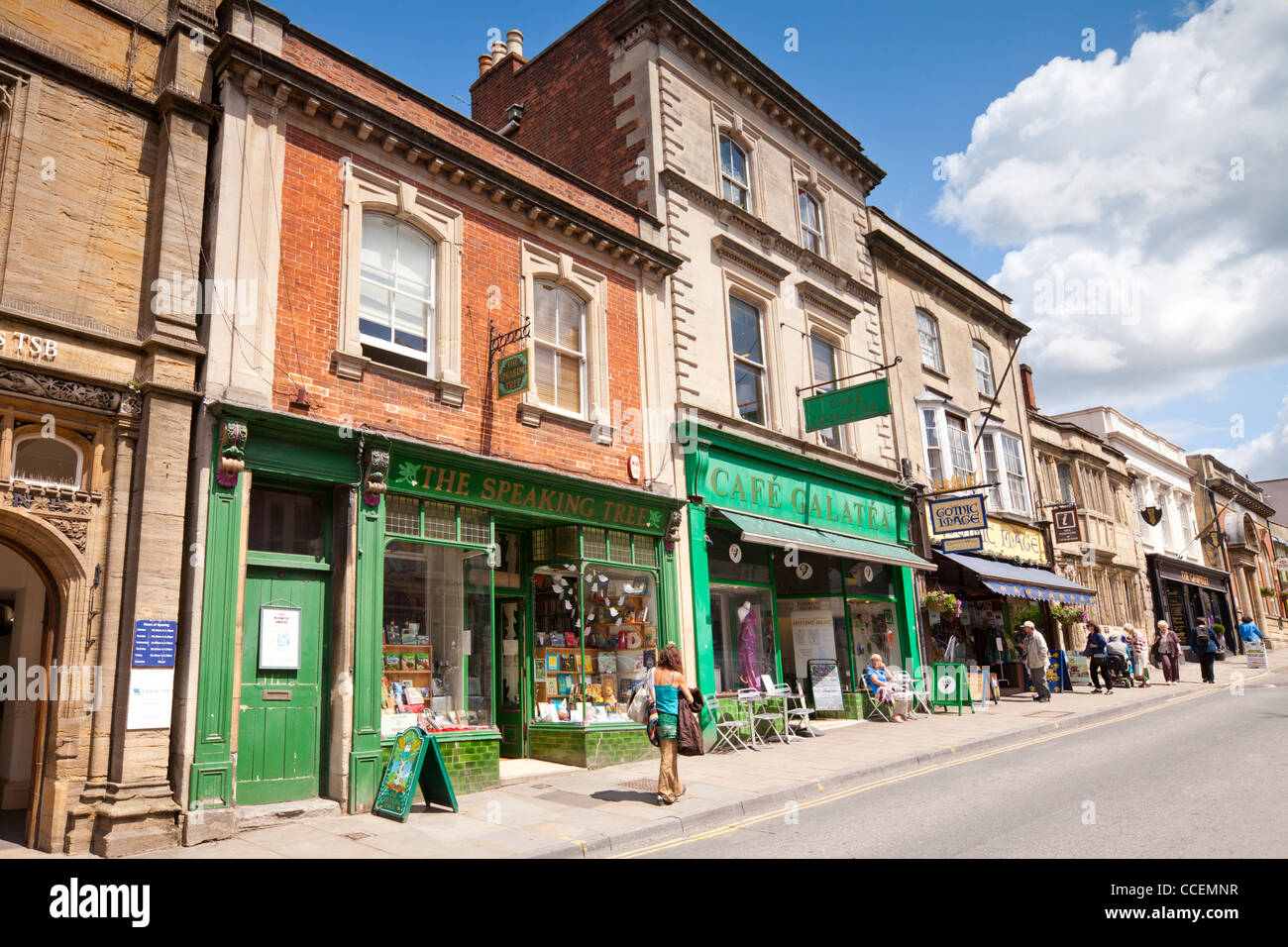 Geschäfte und Cafés und Menschen beim Einkaufen in High Street, Glastonbury, Somerset, England. Stockfoto