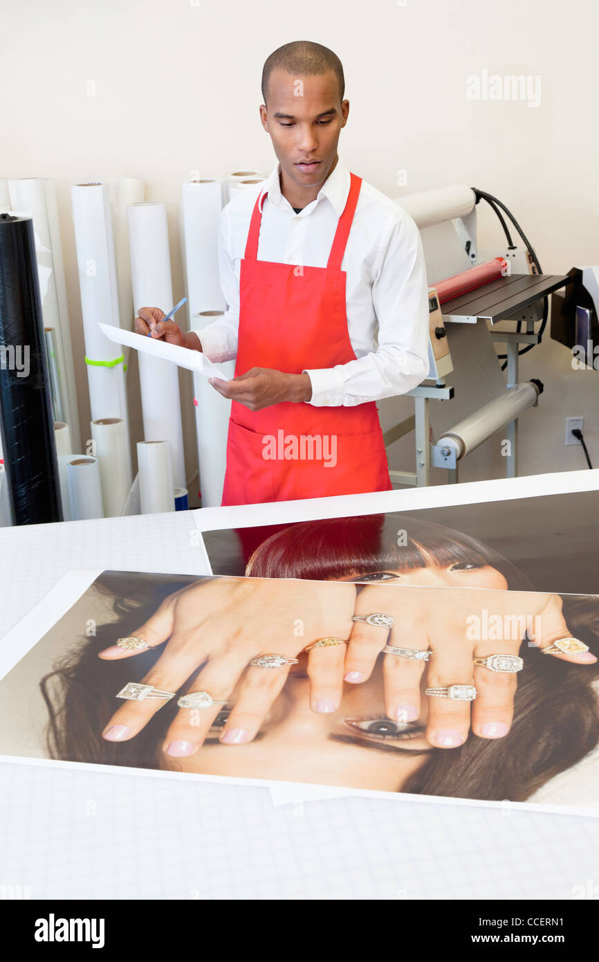 Mann arbeitet an Druckmaschine mit Foto-Ausdrucke auf Tisch Stockfoto