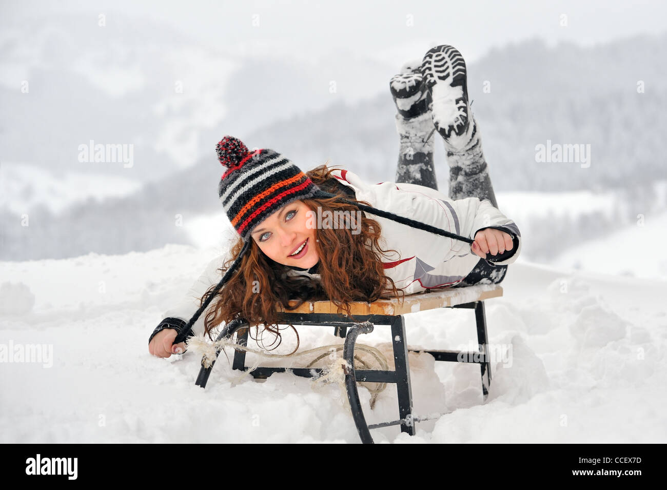 Junge schöne Frau auf Schlitten im winter Stockfoto