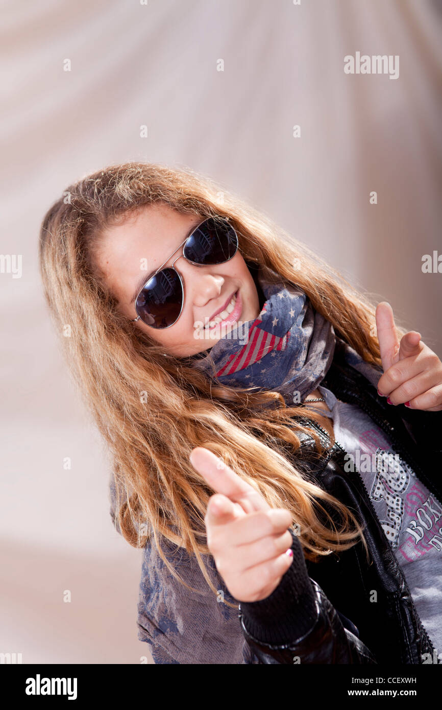 Lächelnde blonde Teenager Sonnenbrille und Waffen mit Händen zu spielen Stockfoto