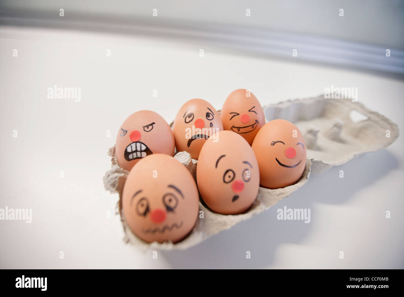 Six-Pack-Eiern mit Gesichtern bemalt in einem Eierkarton Stockfoto