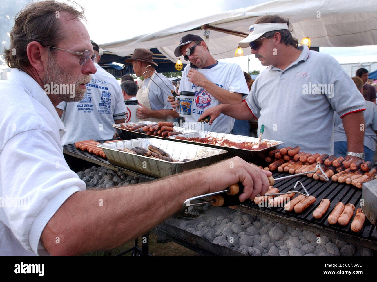 6. August 2004 Kochen - Delhi Township, Ohio, USA - Mitglieder von "The Cubbies von Delhi" Softball-Team, MARTY MOREHEAD(L), DAN HOFFMAN (C) und JEFF BOECKMAN(R), Hotdogs, Gören und Metts am 27. jährliche Delhi Röcke Spiel. (Kredit-Bild: © Ken Stewart/ZUMA Press) Stockfoto