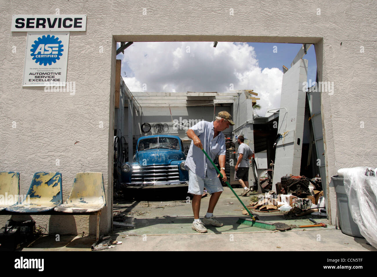 Skip MacKay fegt Schutt aus seinem Hurrikan beschädigt-Shop in Punta Gorda, Florida, Montag, 16. August 2004. Schäden durch Hurrikan Charley wird auf $ 11 Milliarden geschätzt wird. Foto von CHRIS LIVINGSTON / ZUMA Press Stockfoto