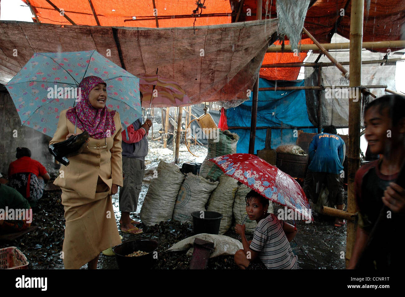 JAKARTA, Indonesien-NOVEMBER 29, Frau Endrizaemi, im Volksmund von "Ibu Haji" geht in der Mitte der Regen auf dem Weg nach Hause von ihrem Studentenhaus, wurde, 2004 von der Schule für Tage abwesend. Neben ihrem Hauptberuf als Leiter des SD Negeri 03 Marunda Grundschule unterrichtet sie auch in Stockfoto