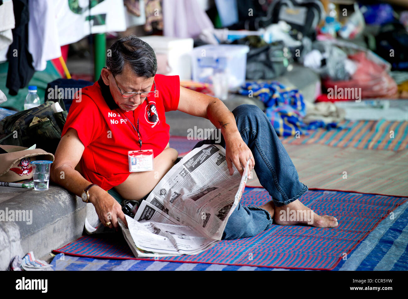 Ein Mitglied der Red Shirts lesen Zeitung während einer Anti-Regierungs-Protest gegen Ratchaprasong. Red Shirts, auch bekannt als Vereinigte Front für Demokratie gegen Diktatur (UDD), Anhänger des gestürzten Ministerpräsidenten Thaksin Shinawatra besetzten Bangkok für über einen Monat in anspruchsvollen thailändische Premierminister Abh Stockfoto