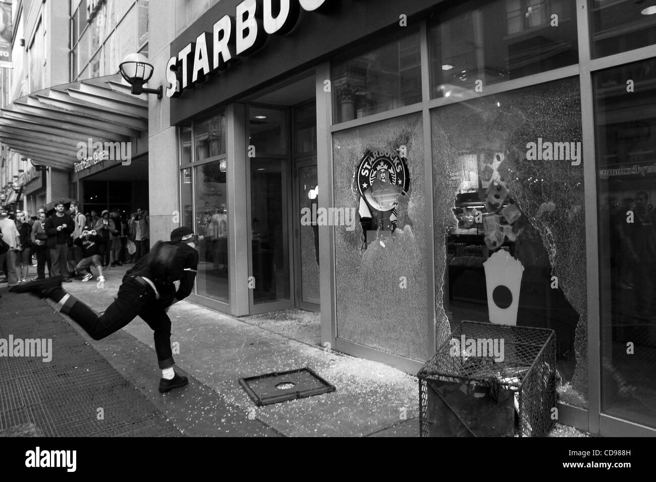 25. Juni 2010 - Toronto, Ontario, Kanada - Black Bloc Demonstrant Zerschlagung ein Starbucks Coffee Windows während des Aufstands in den Straßen von Toronto. Während des G20-Gipfels in Toronto im Juni 2010 ging auf, die schwarzen Blocks auf die Straße gegangen. Die Gruppe von Jugendlichen, die in dunklen farbigen Kapuzen-Sweatshirts, com gekleidet Stockfoto