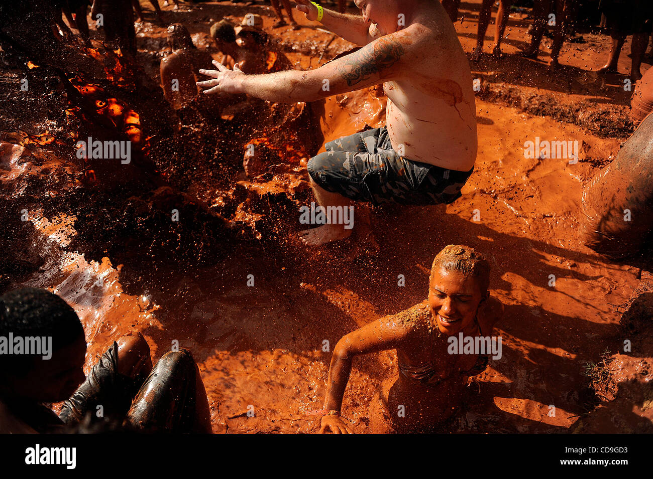 Samstag, 10. Juli 2010 springt EAST DUBLIN, GEORGIA - A Redneck Spiele Teilnehmer über ein Mädchen, wie sie während des Bauchlandung Contest am Buckeye Park während der Redneck Spiele in East Dublin, Georgia im Schlamm wälzt. Die Spiele begannen im Jahr 1996 als Parodie auf die Olympischen Spiele in Atlanta, G statt waren Stockfoto