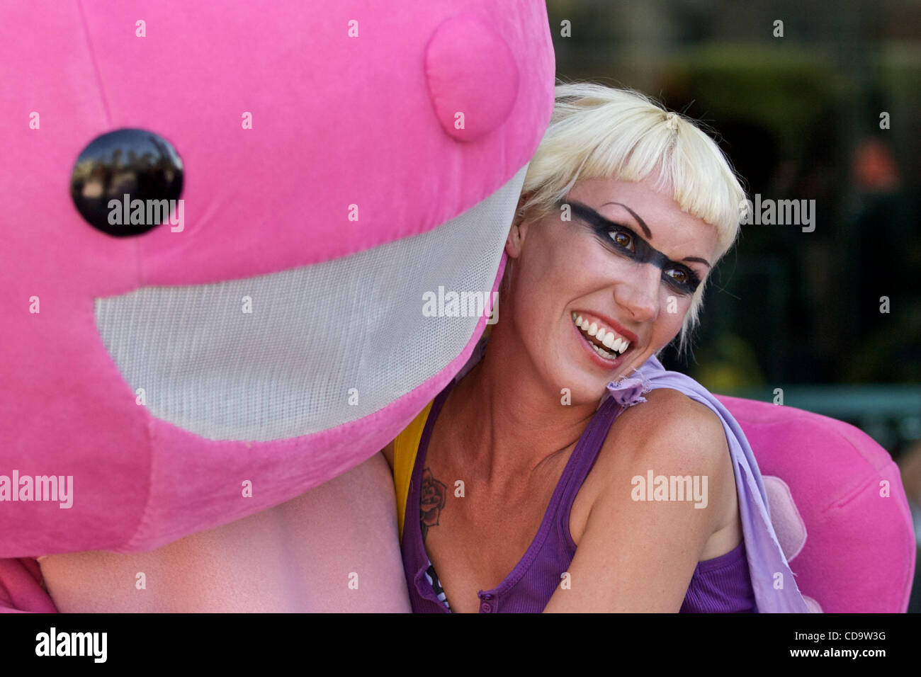 23. Juli 2010 - San Diego, Kalifornien, USA - eine junge Frau genießt die pelzige Umarmung einer niedlichen rosa Kreatur außerhalb der Veranstaltung.  Tausende besuchten Comic Con kostümierten Feierlichkeiten in der Innenstadt von San Diego am Freitag.  Familien, Paare und Kinder - einige geschmückt, in der alles von Ganzanzüge armo Stockfoto