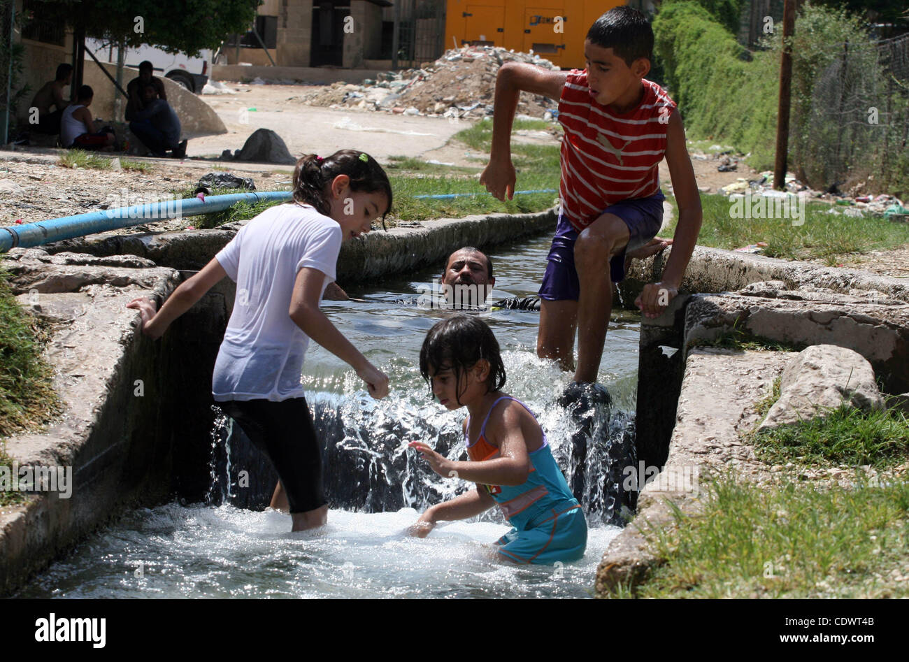 Palästinenser eintauchen in einen Bachlauf des gechannelten Bewässerungswasser wie sie in der biblischen Stadt Jericho abkühlen, wo die Temperaturen bis 47 Grad Celsius, am 30. Juli 2011 stiegen. Foto von Issam Rimawi Stockfoto