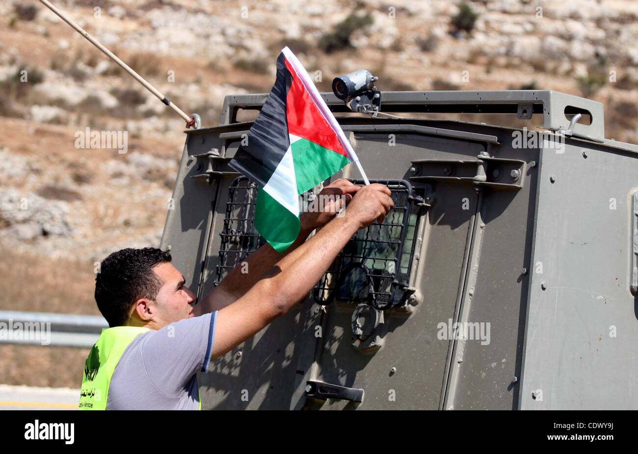 Ein palästinensischer Mann legt seine Nationalflagge auf einem Armee-Jeep während der Einführung von pro-palästinensische Freiwilligen-basierte Kampagne, die eingreifen und reagieren auf Fälle von Gewalt gegen Palästinenser durch jüdische Siedler im Westjordanland, im Westjordanland-Dorf von Nabi Saleh, in der Nähe von Ramallah September 19, Stockfoto