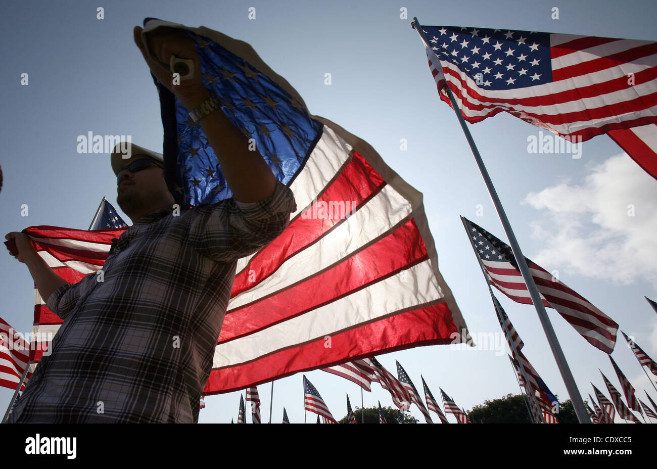 Michael Prince, 38, geht mit einer Fahne unter drei Tausenden von amerikanischen Flaggen an einem Denkmal zu Ehren der Opfer der Terroranschläge 11. September 2001, eingestellt auf Sonntag, 11. September 2011 von Freiwilligen auf dem Campus Rasen der Pepperdine University in Malibu, Kalifornien. (Foto von Ringo Chiu / Zuma Press) Stockfoto