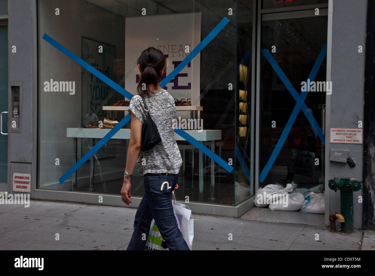 27. August 2011 geht von einem der Schaufenster mit Klebeband in Manhattan - New York, New York, USA - eine Frau. Durch Unwetter verursacht durch eingehende Harricane Irene hat Bürgermeister Bloomberg eine obligatorische Evakuierung der Zone A, Battery Park, stadtweiten umfasst und die Halbinsel Rockaway bestellt. (Credi Stockfoto