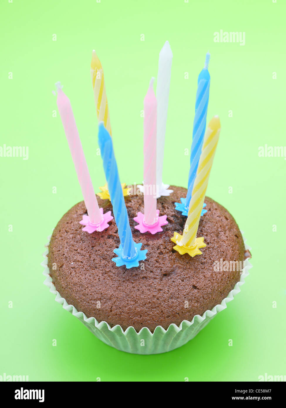 Schoko-Muffin mit acht Kerzen auf hellgrünem Hintergrund Stockfoto