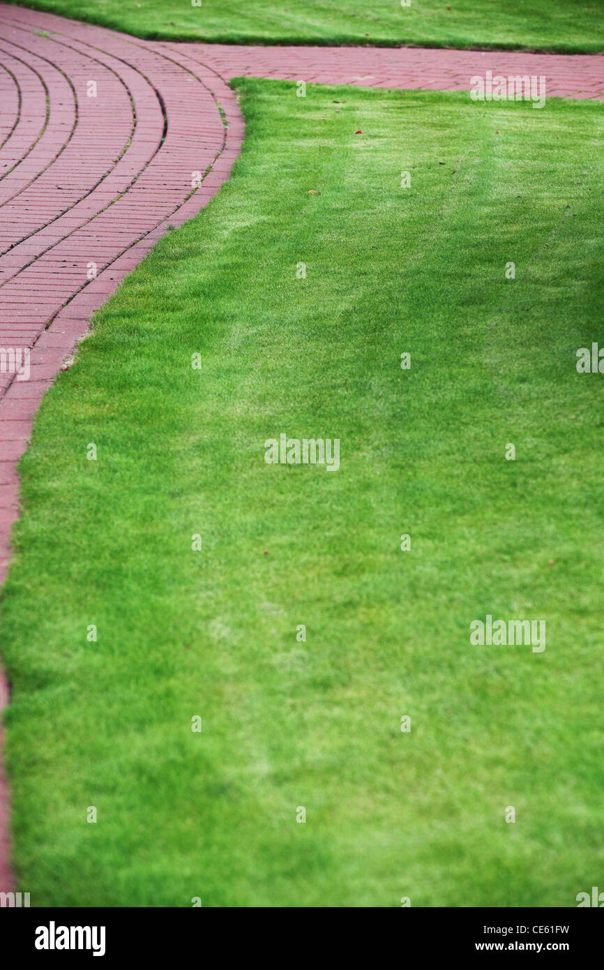 Garten Stein Weg mit Grass aufgewachsen zwischen und rund um Stein, Ziegel Bürgersteig Stockfoto