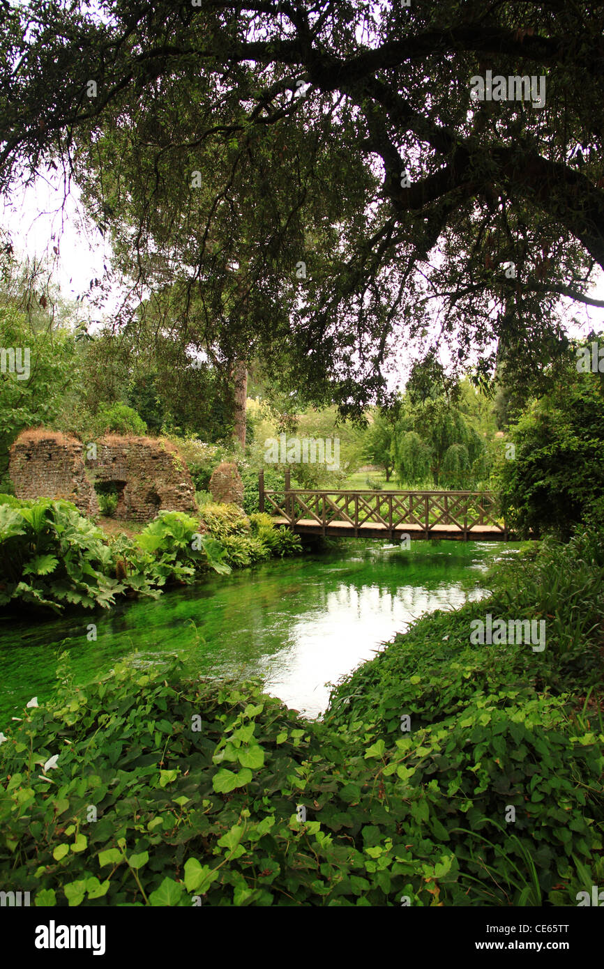 Eine hölzerne Brücke über einem Bach in einem grünen Garten aufgehängt Stockfoto