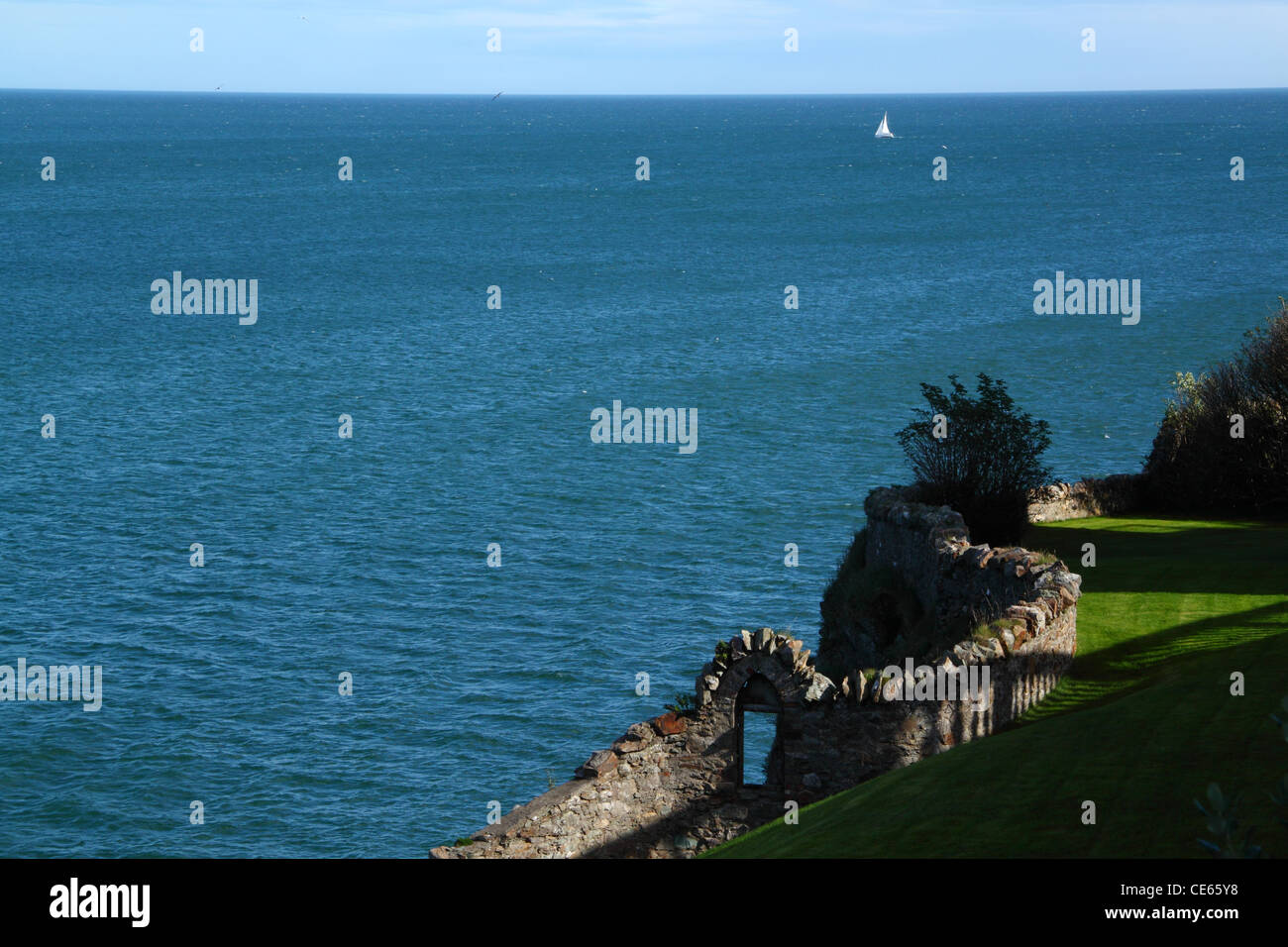 Nur eine alte Steinmauer trennt dieses Gartens aus dem Meer Stockfoto