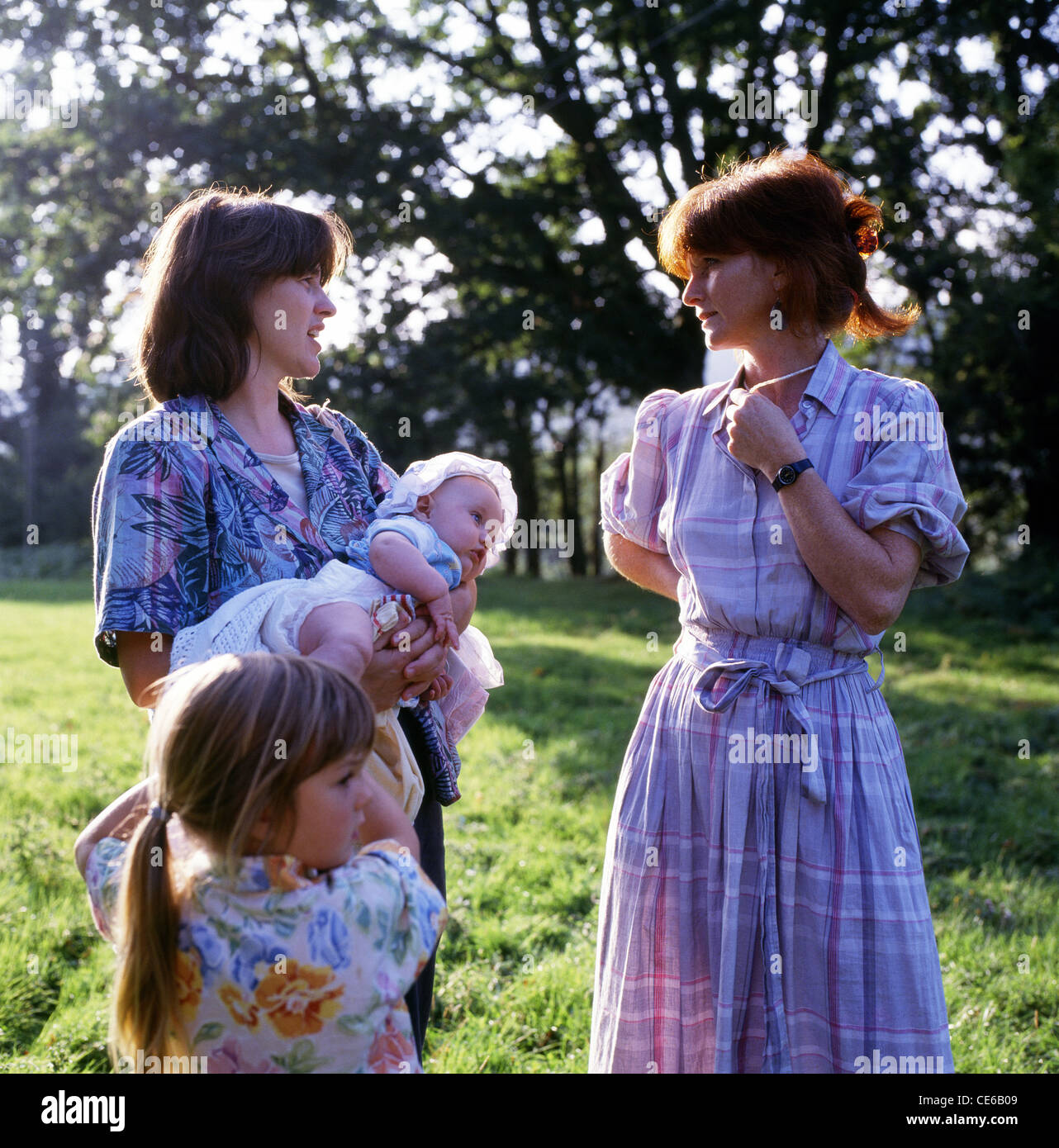 Berufstätige Mütter mit Kindern, die im Sommer im Garten sprechen, nachdem sie 1991 von der Arbeit nach Hause gekommen sind, Wales, Großbritannien, KATHY DEWITT Stockfoto