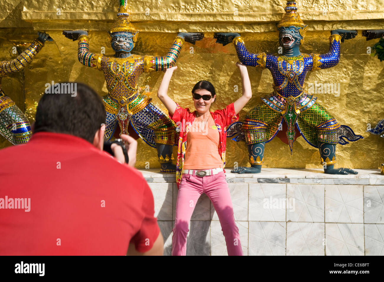 Ein Tourist posiert für ein Foto unter Wächter-Statuen im Wat Phra Kaew.  Bangkok, THAILAND Stockfoto