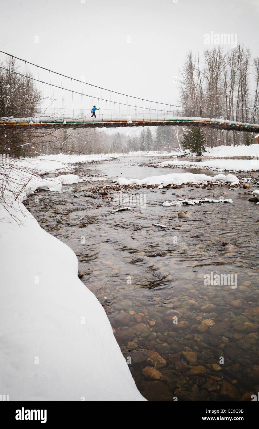 Eine Frau, überqueren die Tawks-Foster-Hängebrücke über den Methow River in der Nähe von Mazama, Washington, USA. Stockfoto