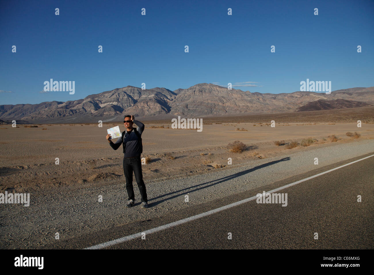 Mann hält Karte am Straßenrand in der Wüste Stockfoto