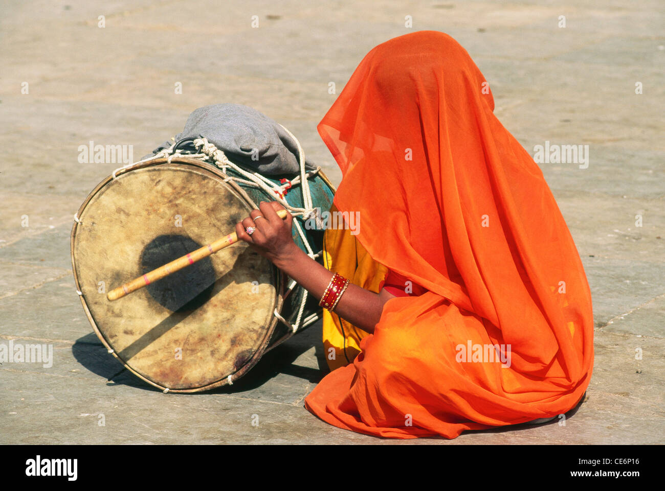 Indische Frau in Schleier Ghunghat schlägt die Trommel am Gangaur Festival; Udaipur; Rajasthan; Indien Stockfoto