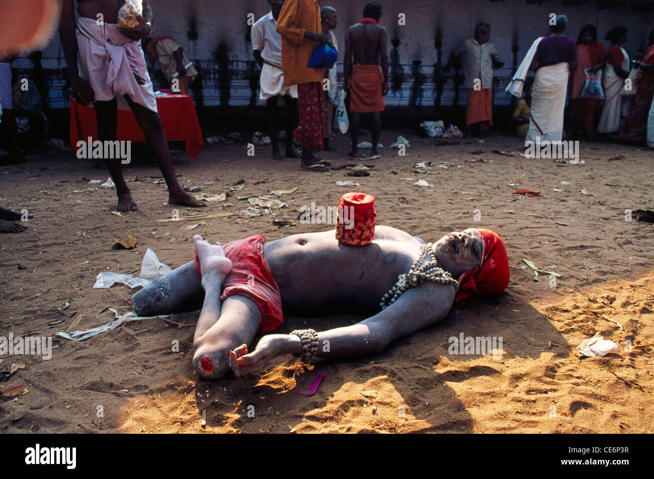 Indischer Bettler mit amputierten Bein; Asche bedeckt roten Lenden Tuch und roten Kopfbedeckung; Kerala; Indien; asien Stockfoto