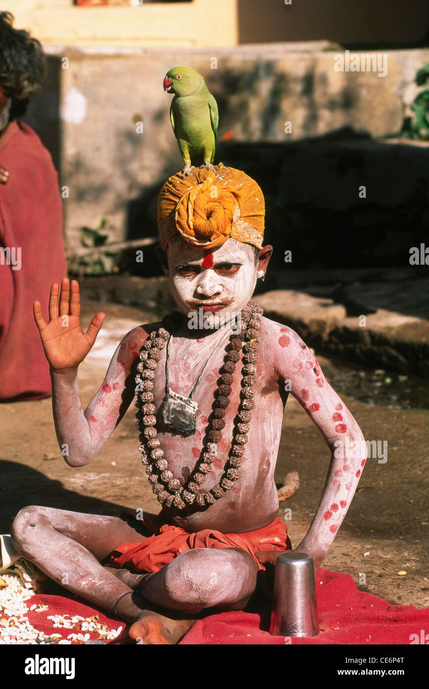 Kind Bettler Segen Pose Asche verschmierten Papagei sitzt auf Kopf Safran Turban Rudraksh Perlen in Pushkar fair; Rajasthan; Indien Stockfoto