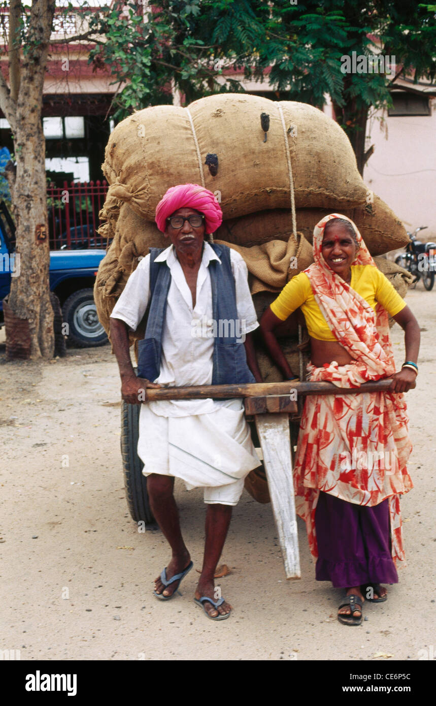 Mann und Frau ziehen Karren, beladen mit Säcken; Nadiad; Gujarat; Indien Stockfoto