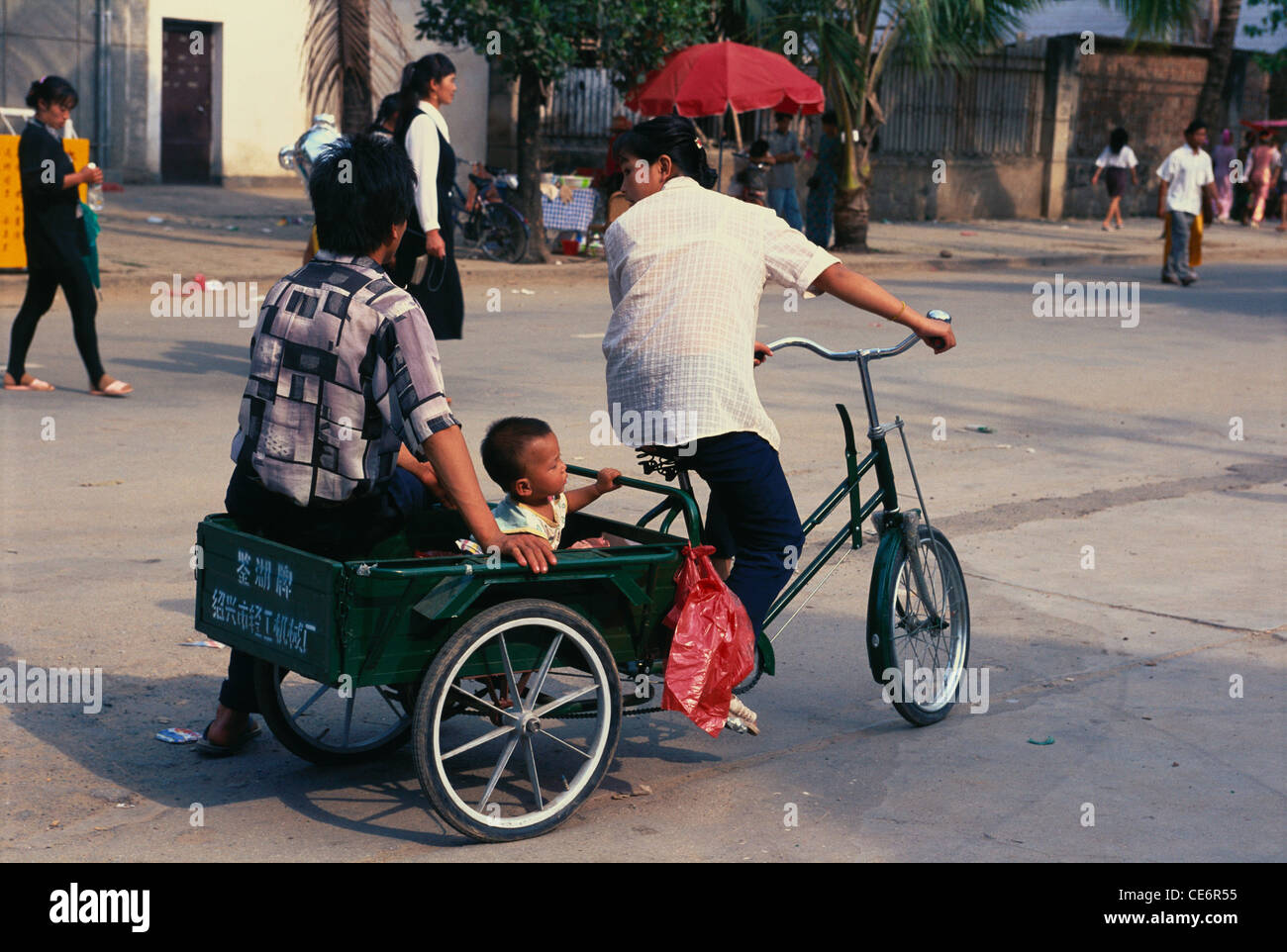 Mann und Kind reiten in Fahrradrikscha; Xishuangbanna; Kunming; Yunnan; China Stockfoto