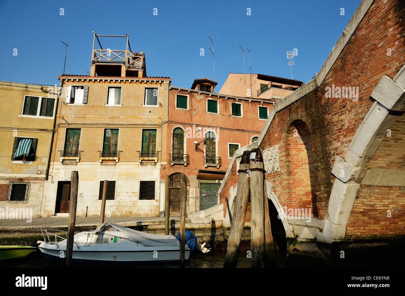 Gebäude und Motorboote am wharf durch Brücke am Kanal, Venedig, Italien Stockfoto